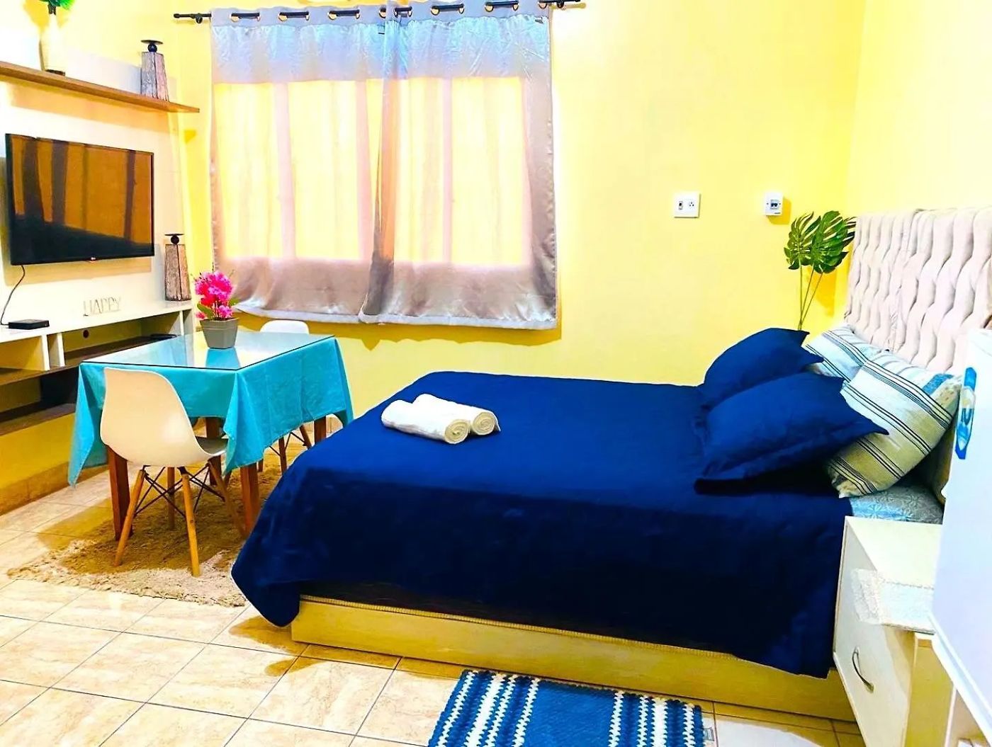 Quarto de casal com cama ampla, mesa de apoio e televisão