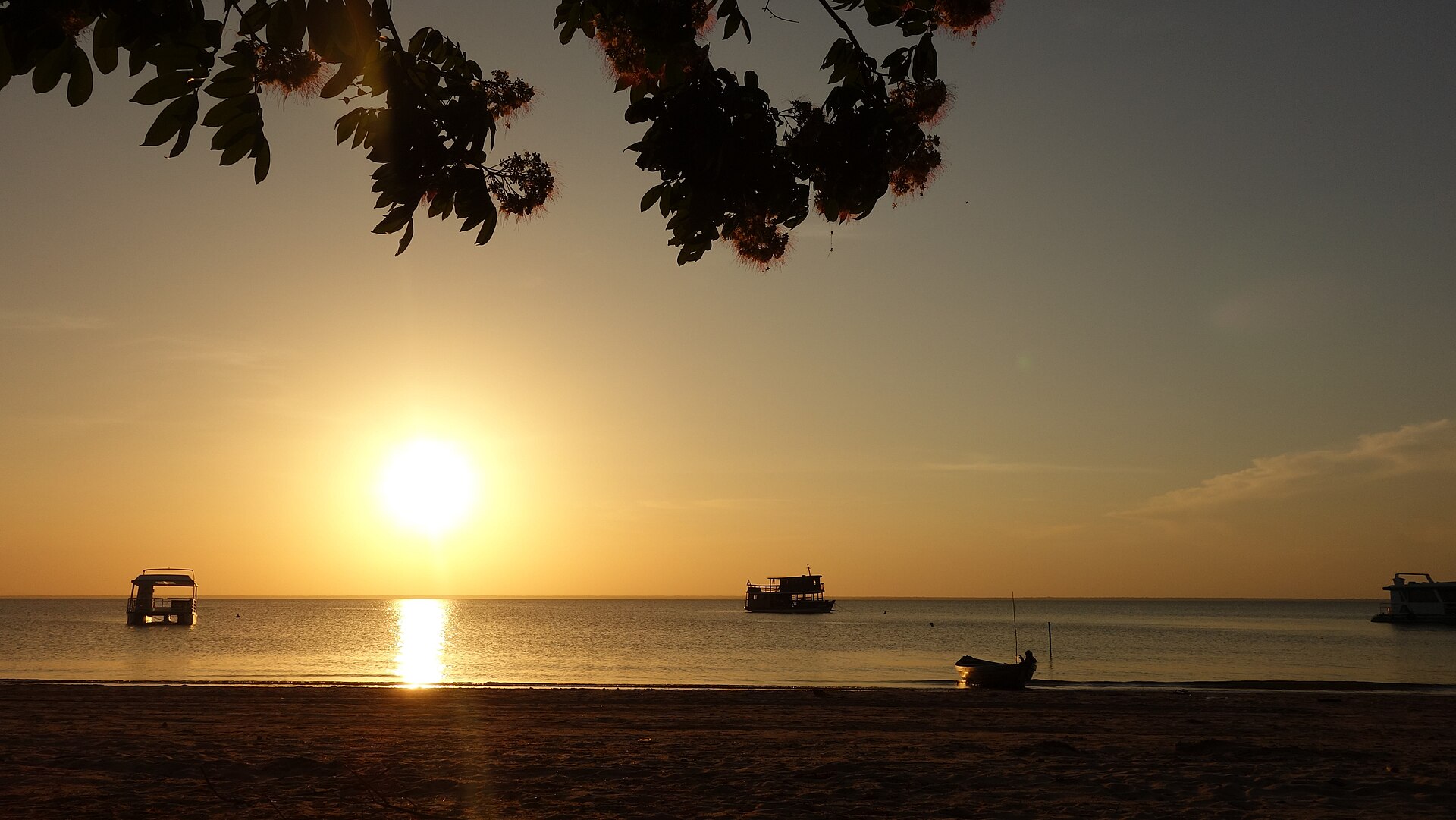 Pôr do sol dourado sobre o Rio Tapajós com barcos ancorados