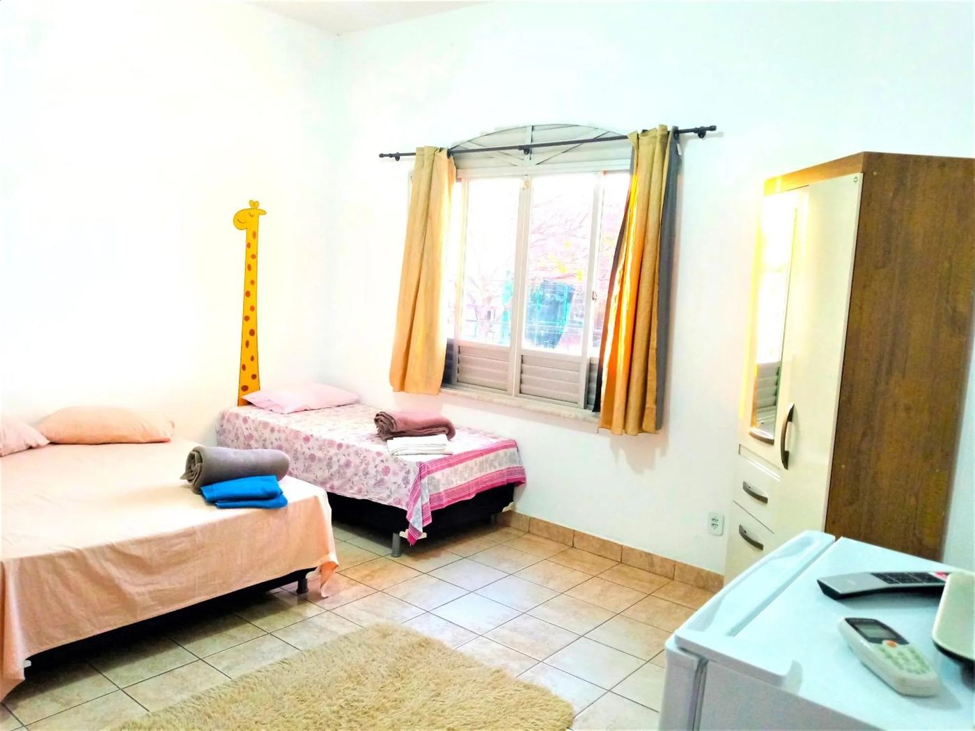 Quarto quádruplo com várias camas, guarda-roupa e janela para a rua