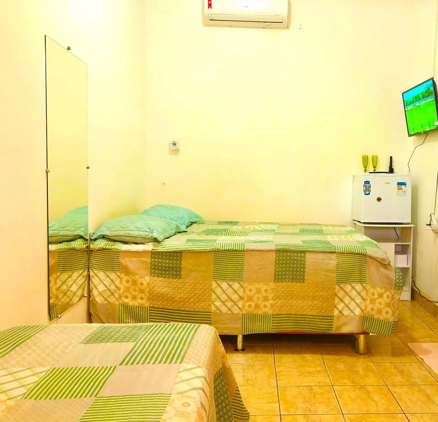 Quarto quádruplo com camas lado a lado, frigobar e televisão